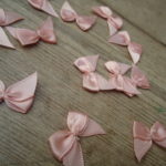 Salmon Pink satin ribbon bows, 15 in a pack, dressmaking supplies and online haberdashery, pretty ribbon bows for sale, trimmings and accesories for sewing online shop at HandBound Costume Supplies